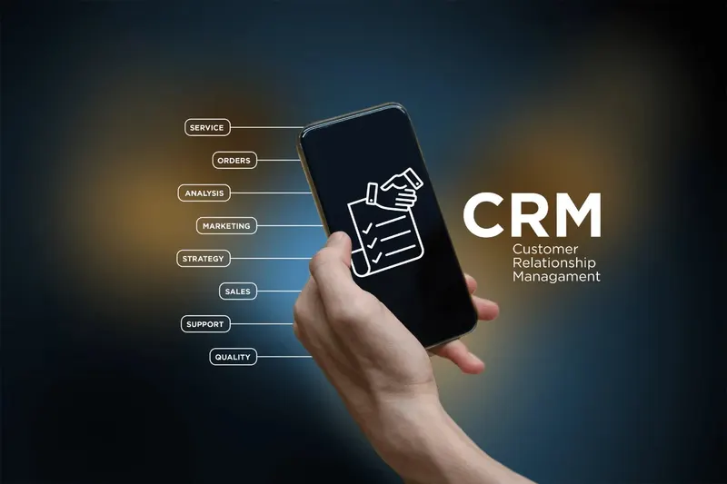 Hand holding a phone beside a CRM illustration