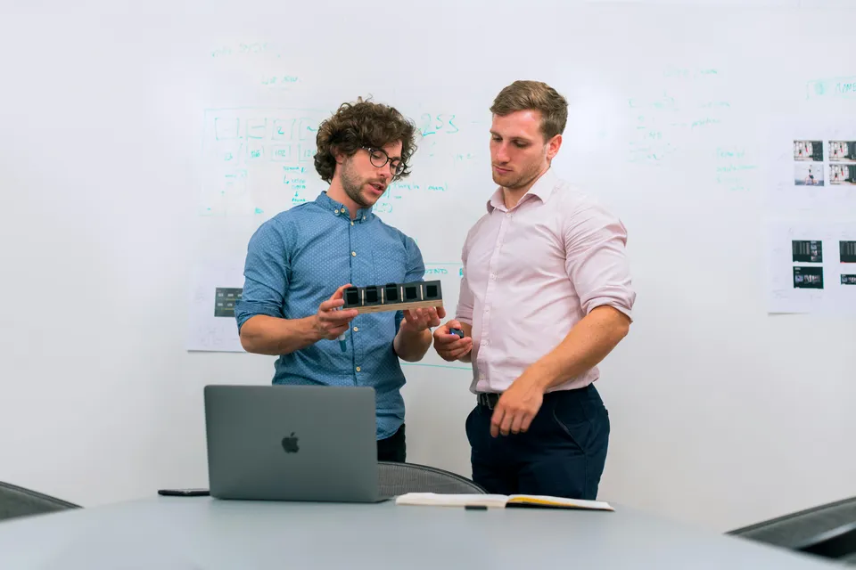 Two people discussing a design beside a laptop